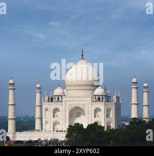 Teleobiettivo distante del sole che splende brillantemente sul marmo bianco del Taj Mahal dall'esterno del parco durante il giorno sotto lo splendido cielo blu ad Agra, i Foto Stock