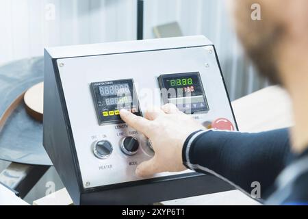 Primo piano dell'operatore, l'operatore preme il pulsante sul pannello di controllo con i dispositivi di controllo nella produzione di mobili. La mano di quell'uomo presse Foto Stock