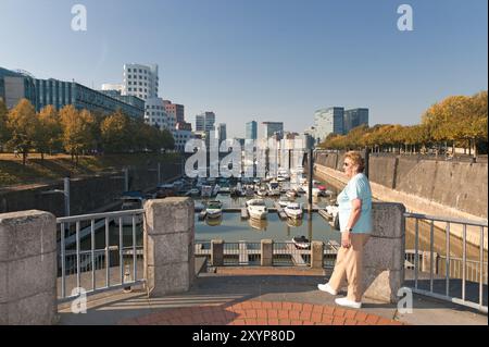 Seniorin steht an der Treppe am Duesseldorfer Stadthafen Foto Stock