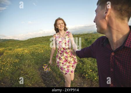 Giovane coppia sposata. Il tizio conduce una ragazza riccia con un mazzo di fiori. Il concetto di fiducia e famiglia giovane felice Foto Stock