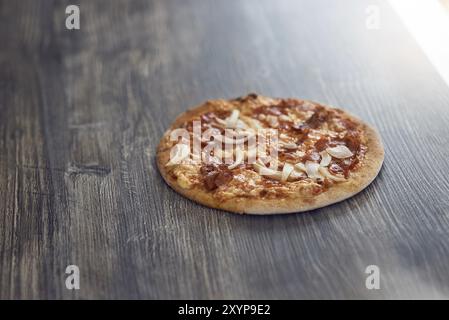 Appena cotto alla griglia di fiamma pizza italiana su una crosta croccante su un contatore di legno in una pizzeria con copia spazio sopra Foto Stock