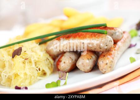 Tradizionale piatto tedesco di salsiccia di vitello con crauti e involtini di spaghetti con birra Foto Stock