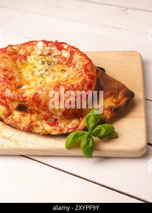 Una gustosa pizza calzone su un tagliere di legno Foto Stock