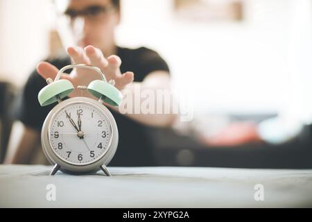 L'uomo sta spingendo una sveglia, il sole al mattino, sfondo sfocato Foto Stock