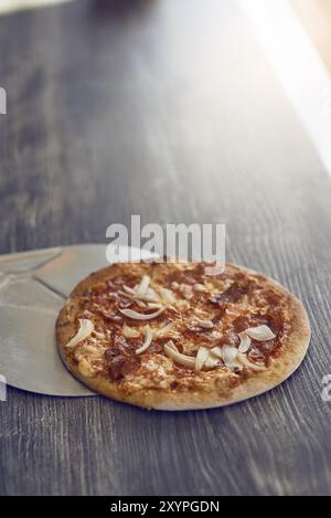 Appena cotto alla griglia di fiamma pizza italiana su una crosta croccante su un contatore di legno in una pizzeria con copia spazio sopra Foto Stock