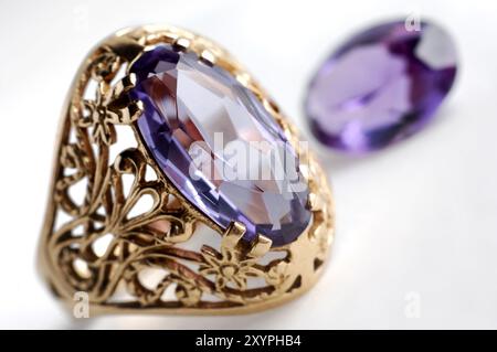 Anello d'oro con alessandrite e gemme di alessandrite in primo piano di gioielli isolati sul bianco Foto Stock