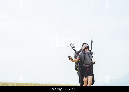Primo piano di un parapendio professionista che tiene i freni e guarda lontano. Concetto di sport parapendio Foto Stock