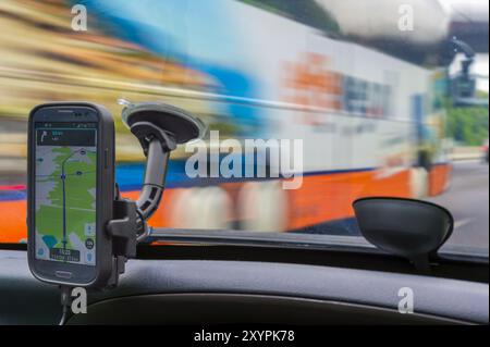 Guardando attraverso il parabrezza di un'auto oltre il navigatore satellitare di un autobus in sorpasso Foto Stock