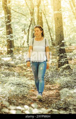 Caucasian giovane donna è percorribile a piedi in legno, autunno Foto Stock