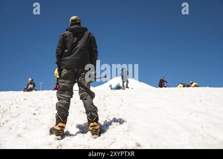 Allenamento per correggere lo scivolamento su un pendio o su un ghiacciaio con l'aiuto di un'ascia di ghiaccio. Una giovane guida con la barba spiega al suo gruppo come rallentare correttamente il Foto Stock