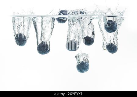 I mirtilli che affonda nell'acqua con bolle di aria sullo sfondo bianco Foto Stock