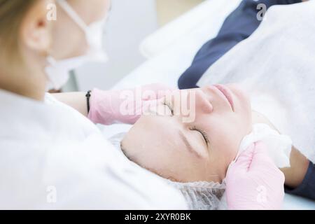 Un primo piano della procedura di pulizia nell'ufficio di cosmetologia. Pulizia della pelle con schiuma. Bella ragazza nel salone di bellezza per la pulizia del viso Foto Stock