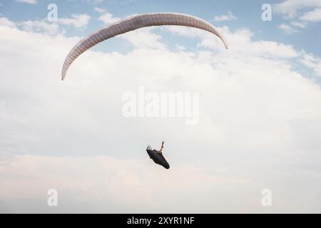 Parapendio da solo che vola nel cielo blu sullo sfondo delle nuvole. Parapendio nel cielo in una giornata di sole Foto Stock