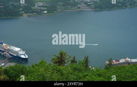 Un piccolo idrovolante atterra nel canale di Gastineau a Juneau, Alaska, con navi da crociera attraccate nelle vicinanze Foto Stock