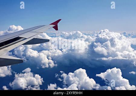 Vista dell'ala di un aeroplano sopra splendide nuvole al sole e al cielo blu Foto Stock