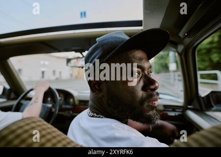 Medio primo piano di un uomo seduto sul sedile anteriore e guardando indietro Foto Stock