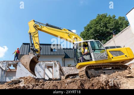 Processo di demolizione di un vecchio edificio. Rottura dell'escavatore. Distruzione di alloggi fatiscenti per un nuovo sviluppo Foto Stock