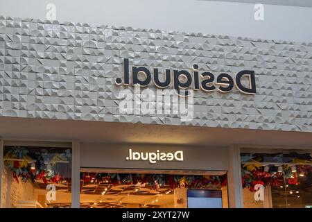 Primo piano del cartello con il logo Desigual presso il loro negozio in un centro commerciale. Foto Stock