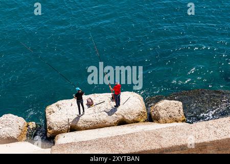 Pescatori sul blocco di roccia, vista dalla Cittadella di Qaitbay, sull'antica isola di Pharos (ora penisola) del Mar Mediterraneo, Alessandria, Egitto, Nord Africa Foto Stock