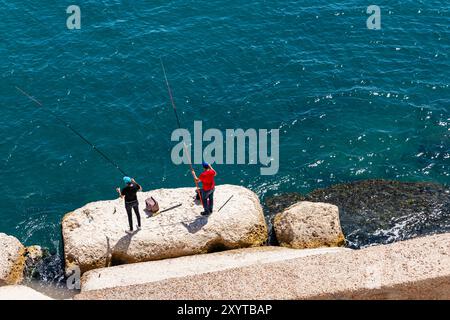 Pescatori sul blocco di roccia, vista dalla Cittadella di Qaitbay, sull'antica isola di Pharos (ora penisola) del Mar Mediterraneo, Alessandria, Egitto, Nord Africa Foto Stock