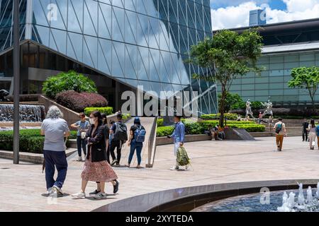 Hong Kong, Cina - 3 luglio 2024: Una vista su una piazza moderna a Hong Kong, Cina. Le persone camminano e si siedono vicino a una fontana con statue nel ce Foto Stock