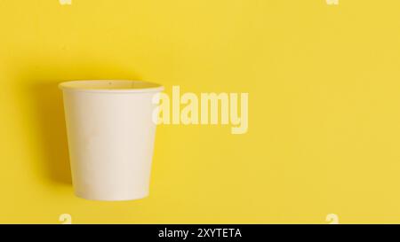 Tazza di carta monouso per caffè e tè su sfondo arancione brillante. Foto Stock