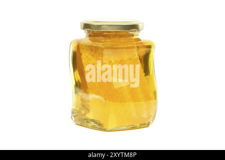 Un vaso di vetro con coperchio dorato contiene miele con favo riempito quasi fino in cima, su sfondo bianco Foto Stock