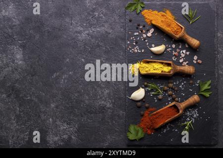 Spezie ed erbe su fondo di pietra nera. Vista dall'alto con spazio libero per menu o ricette Foto Stock