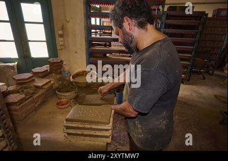 Uomo che forma mattoni di argilla in un laboratorio di ceramica tradizionale con luce naturale, mattoni Patmos cotto, fabbricazione tradizionale di mattoni, Kampos, Patmos, Dode Foto Stock