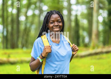 Ritratto di una giovane donna africana felice che cammina attraverso la foresta verde Foto Stock