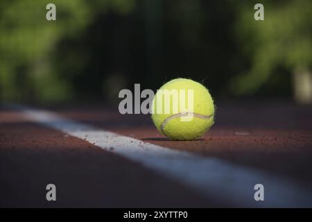 Palla da tennis gialla sulla superficie del campo duro vicino alla linea bianca con vista ad angolo basso Foto Stock