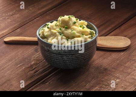 Pomme purea, una foto di una tazza di purea di patate con erbe al buio su un sfondo rustico con un mestolo di legno e spazio di copia Foto Stock