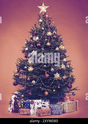 Splendido albero di Natale stilizzato vintage decorato con regali avvolti sotto. Isolato su sfondo marrone Foto Stock