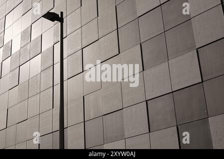 Dettaglio della facciata di un edificio moderno a Magdeburgo. La facciata e' rivestita con lastre di pietra quadrate in uno schema a scacchiera. In primo piano c'è una S. Foto Stock