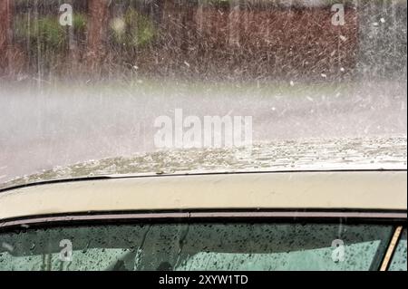 Pioggia e grandine cadono sul tetto di un'auto Foto Stock