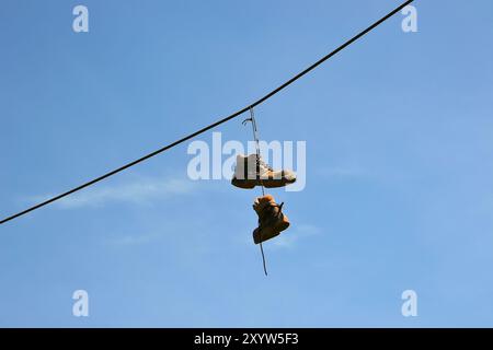 Scarpe appese a una linea aerea a un'altezza elevata Foto Stock