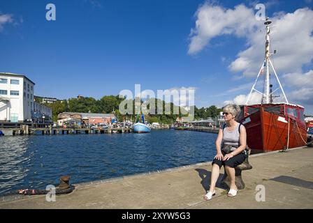 Donna seduta sulla banchina nel porto di Sassnitz Foto Stock