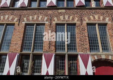 Vista dettagliata di un edificio in mattoni con grandi finestre e persiane rosse e bianche sotto un cielo blu, Xanten, basso Reno, Renania settentrionale-Vestfalia, Germania Foto Stock