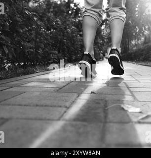 Runner piedi in esecuzione su strada closeup sulle scarpe. Donna fitness jog sunrise allenamento concetto di benessere. In bianco e nero Foto Stock