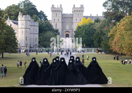 Windsor, Regno Unito. 30 agosto 2024. Le maree petrolifere di Extinction Rebellion si esibiscono durante la lunga passeggiata fuori dal Castello di Windsor durante una protesta "il sistema è rotto" durante il primo dei tre giorni di attività di Upgrade Democracy. La campagna “Upgrade Democracy” di Extinction Rebellion ha lo scopo di evidenziare il modo in cui i profitti sono salvaguardati per le compagnie petrolifere e del gas nel Regno Unito e di invitare il governo britannico a creare e a essere guidato da un’Assemblea dei cittadini sul clima e la giustizia ecologica. Crediti: Mark Kerrison/Alamy Live News Foto Stock