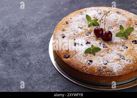 Fatta in casa torta di ciliegie con lo zucchero a velo e menta su nero sfondo rustico Foto Stock