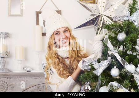 Felice giovane donna bionda vicino all'albero di Natale con decorazioni Foto Stock