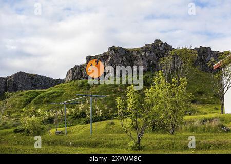 DJUPIVOGUR, ISLANDA, 21 GIUGNO: Sole arancione rotondo con tre uccelli neri appeso da una montagna il 21 giugno 2013 a Djupivogur, Islanda, Europa Foto Stock