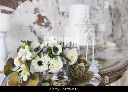 Bianco torta di nozze con decorazioni di argento e bouquet nozze con ranunculus Foto Stock