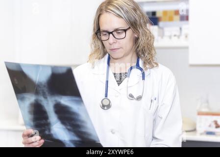 COVID-19. Medico donna che tiene in mano una radiografia dei polmoni di un paziente. Concetto di rilevamento di malattie polmonari, diagnosi di polmonite e coronovirus Foto Stock