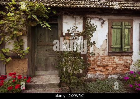 Vecchia casa semi-abbandonata in legno con porta e finestra Foto Stock