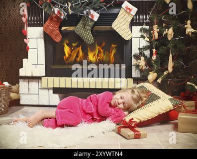 Poco carino ragazza dorme sotto l albero di Natale in attesa di Babbo Natale a venire Foto Stock