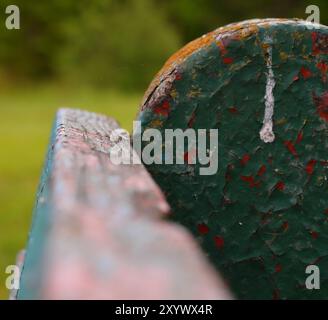 scheggiatura di strati di vernice sulla vecchia panchina del parco, primo piano / macrofotografia Foto Stock