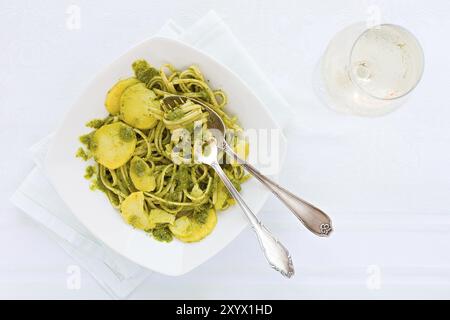 Linguine con pesto genovese, patate e vino bianco bicchiere visto da sopra Foto Stock