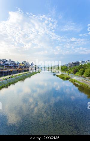 KYOTO, GIAPPONE, 20 GIUGNO 2015: Persone riposanti e ristoranti fiancheggiano le rive del fiume Kamo nel tardo pomeriggio in una giornata di cielo blu nel centro Foto Stock